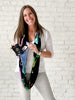 woman wearing waypoint goods travel scarf with a hidden zipper pocket made from lightweight bamboo and cotton fabric and a watercolor world map design