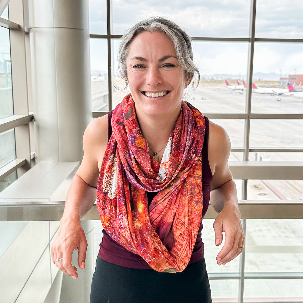woman wearing jasmine and jain travel scarf by waypoint goods at an airport